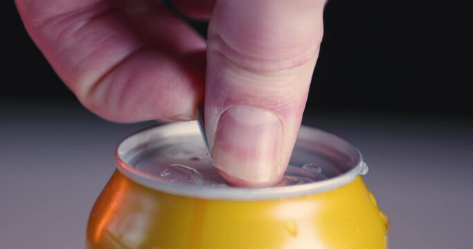 Yellow soda can soft drink with condensed water is opened, close-up, slow-motion