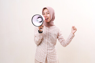 Happy young asian muslim girl celebrating her success using megaphone. Isolated on white