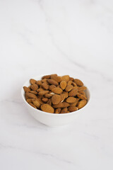 Almonds in a white bowl on a marble table
