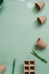 Gardening concept. Planting seedlings of vegetable or flower crops in the house. Peat cassettes for seedlings, garden pots, tools on a green background. Flat lay, copy space