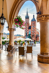 Restaurant table and chairs on old town in Cracow, Poland. View from Cloth hall at sunrise - obrazy, fototapety, plakaty
