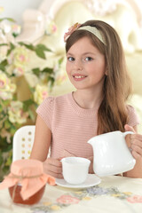 Smiling girl drinking tea at the table