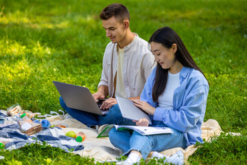 Young people sitting on the grass and preparing to the exams