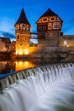 Historic castle tower and museum in old town of Balingen at a cascade of Eyach river in Baden-Wuerttemberg, Germany. Half timbered and illuminated facades at idyllic evening twilight in winter season.
