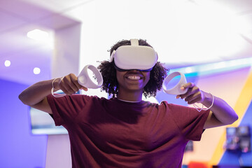 African American girl playing with virtual reality glasses and controllers while laughing