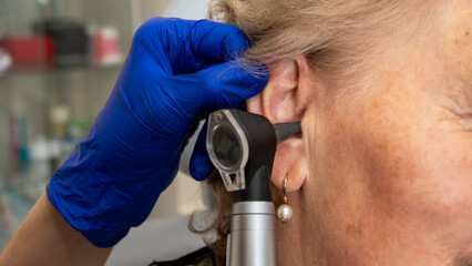 Otolaryngologist's office, doctor's examination of an elderly woman's ear, ear plug, hearing test