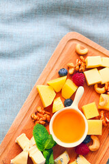 Cheese, honey, berries and nuts on wooden board