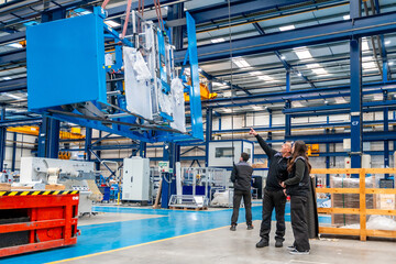 Team of engineers lifting heavy machinery using a crane