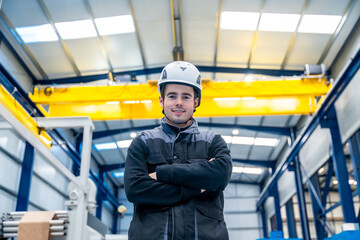 Manual worker with helmet standing proud in a factory