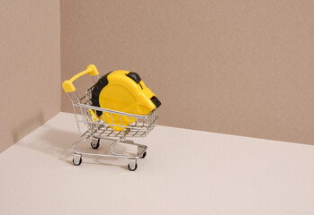 Yellow tape measure and shopping cart. Copy space for text.