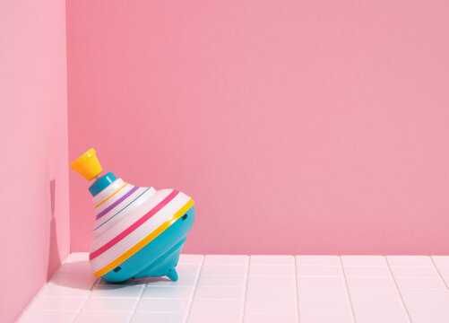 Colorful fun spinning top on a pink background. Copy space for text.