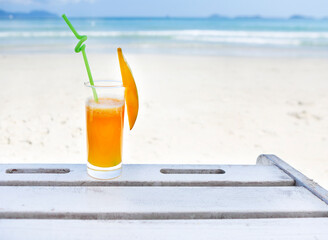 Glass of orange colour juice on the beach
