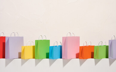 Colorful brightly colored shopping bags of different sizes stand in a row. Copy space for text. Idea of shopping and spending money.
