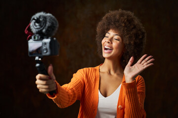 Live broadcast on social networks, a young Latina with afro hair uses the camera to record video
