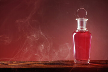 bottle with magic potion in smoke on red backround