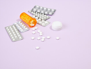 Capsules and tablets in blister packs on table. White pills scattered from the orange pill jar. Copy space for text.