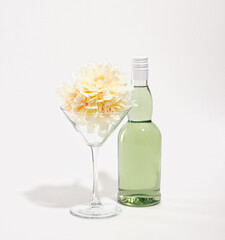 Glass bottle with green alcoholic beverage, cocktail glass with a beautiful flowers isolated on white background.