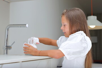Little girl washing dish in kitchen, kid doing house chores