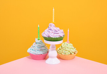 Delicious fresh creamy cupcakes with colored sprinkles and festive candles.