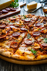 Circle pizza chorizo with chicken nuggets and mozzarella, on wooden table
