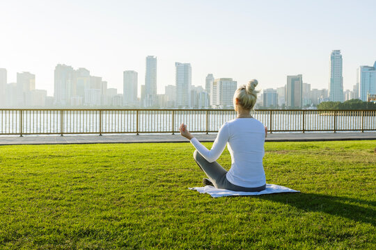  mature woman  in sporty outfit  meditation in park at sunrise.