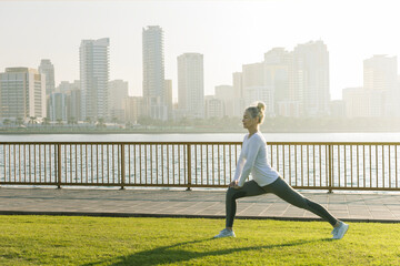 woman  making stretching before running along seaside.  senior woman practices yoga outdoors at...