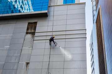  Worker washes wall facade at height on modern building.