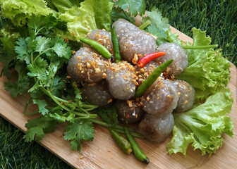 Tapioca Balls with Pork Filling with deep-fried garlic, green lettuce, and coriander on the wooden plate