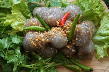 Close-up of Tapioca Balls with Pork Filling with deep-fried garlic, green lettuce, and coriander on the wooden plate