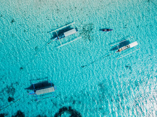 Fishing boats at anchor in blue sea in tropical island. Aerial view.