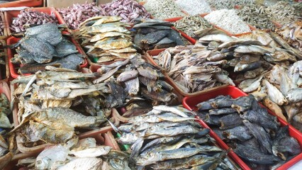 Various kinds of salted fish in containers at a traditional market
