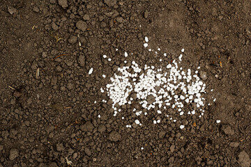 fertilizer granules on a dark brown background. Close-up. Root feeding. Preparatory work in the...