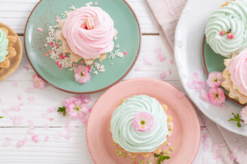 pink and green cupcakes with spring flowers on white wooden background