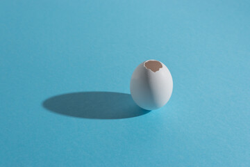 White egg shell on bright blue background. Minimal Easter concept.