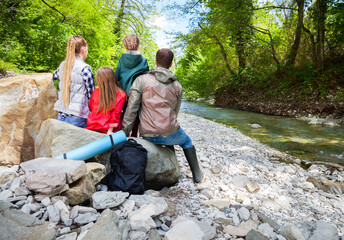 Happy young family with two little daughters near the mountain river