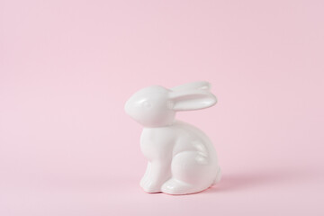 Porcelain white Easter bunny on pastel pink background. Minimal Easter concept.