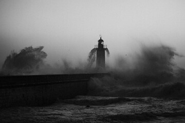 Portuguese Lighthouse with stormy Atlantic wave. Black and white photo with film noise effect.