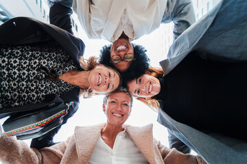 Bottom view of a group of business women standing on a circle together smiling and looking down to...