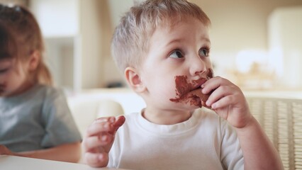 children eat chocolate. dirty little lifestyle baby kids in the kitchen eating chocolate in the...