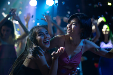 Sexy young woman people dancing and holding champagne glass in night club. Happy fun Asian people...