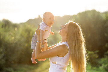 Happy young mother playing and having fun with her little baby son on sunshine warm spring or...