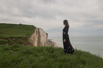woman in classic vintage dress standing on a cliff near Etretat, Normandy, France
