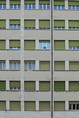 facade of an anonymous building in a working-class neighborhood with windows with some shutters pulled down closed and others open