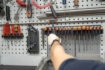 A worker in a locksmith workshop selects a screwdriver for work.