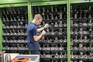 A worker inspects and selects a cutter from a rack to use on a CNC machine.