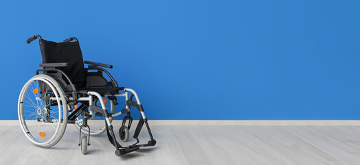 Modern empty wheelchair near blue wall. Banner for design