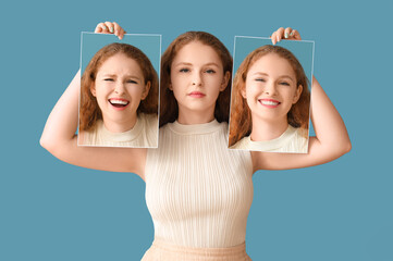 Young woman holding posters with different emotions on blue background