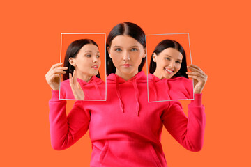Young woman holding posters with different emotions on orange background