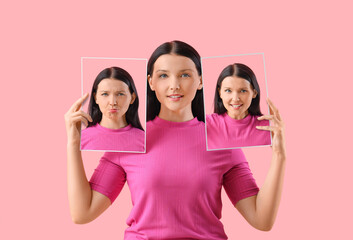 Young woman holding posters with different emotions on pink background
