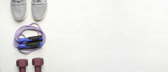 Skipping rope with sneakers and dumbbells on white grunge background with space for text